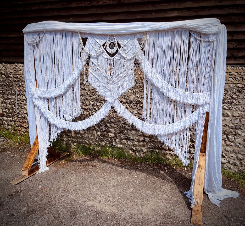 Large macrame backdrop on wooden stand